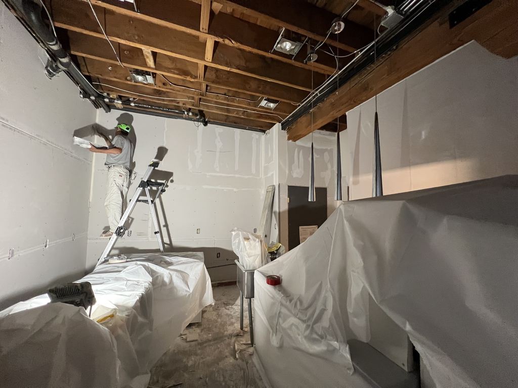 During: new drywall ceiling going in, with finished areas wrapped in plastic
