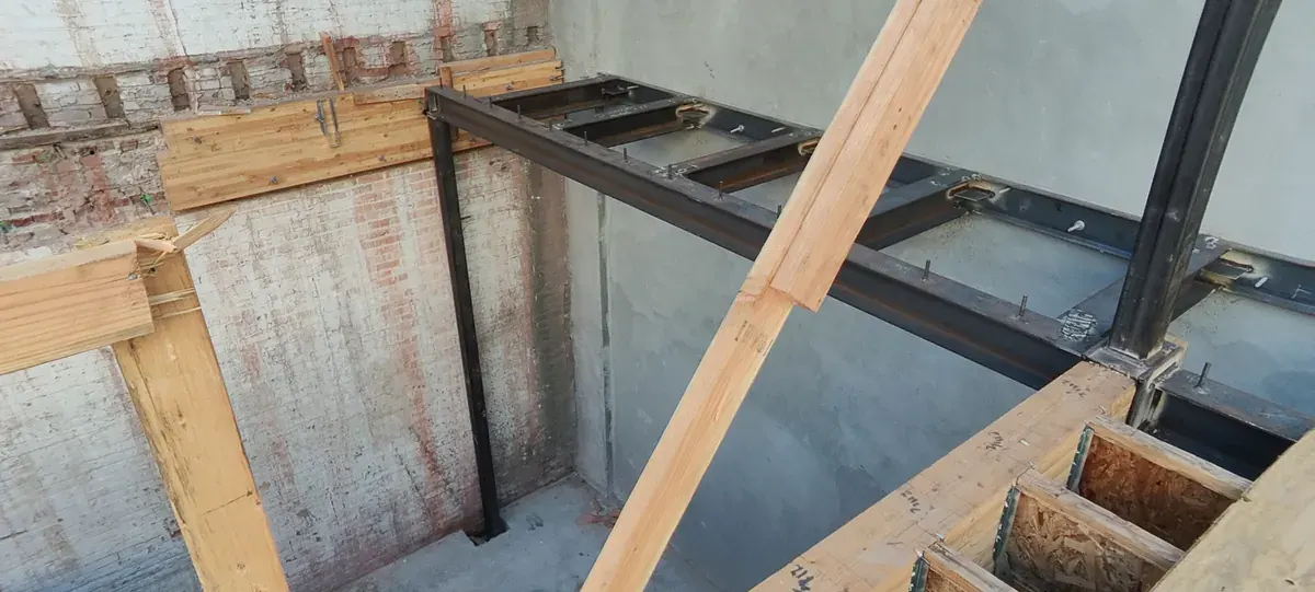 New steel beams and wood floor framing against the original brick wall after a fire, Bluxome St, San Francisco